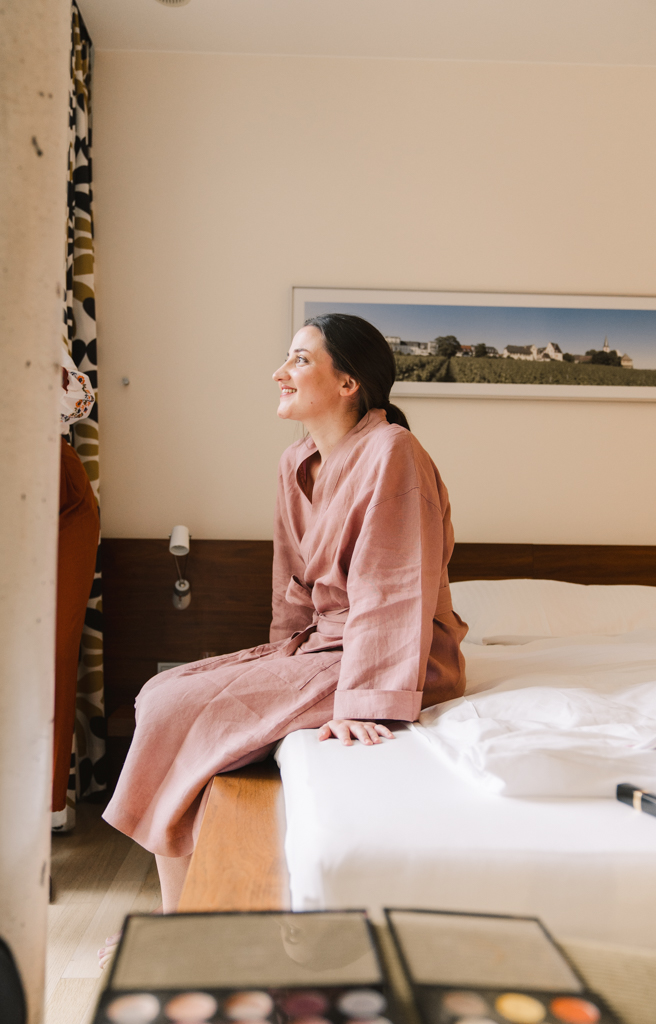 Braut sitzt auf dem Bett im Hotelzimmer.