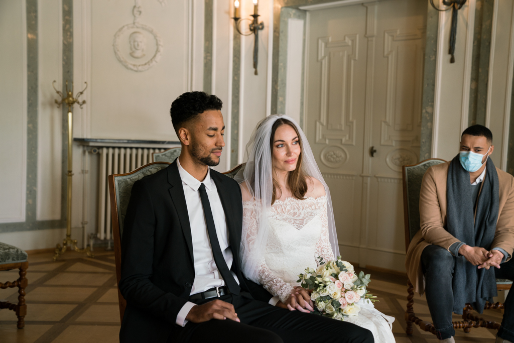 Hochzeit während Corona Brautpaat sitzt im Standesamt ohne Maske.