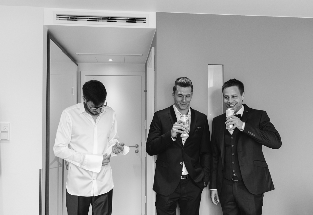 Trauzeugen des Bräutigams trinken im Hotelzimmer ein Bier zusammen.