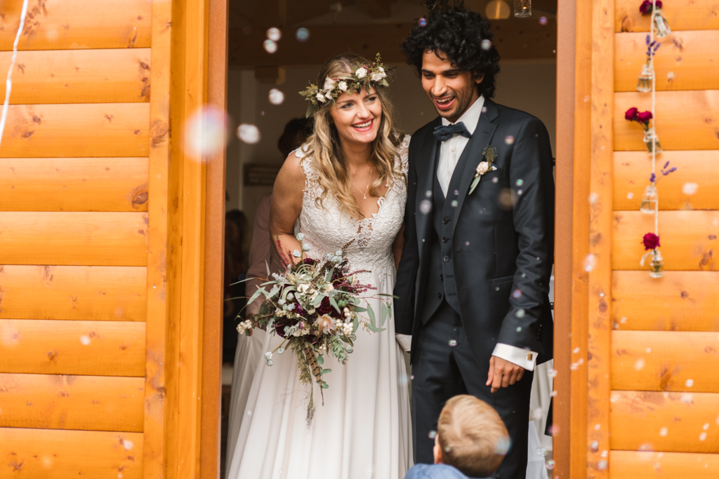 Hochzeitspaar verlässt den Trausaal und wird mit Seifenblsen von der Hochzeitsgesellschaft begrüßt.