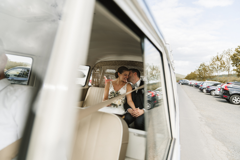 Brautpaar sitzt auf der Rückbank eines Vw Buses nach der Hochzeit jetzt auf dem Weg zum Heckers in Gründau.