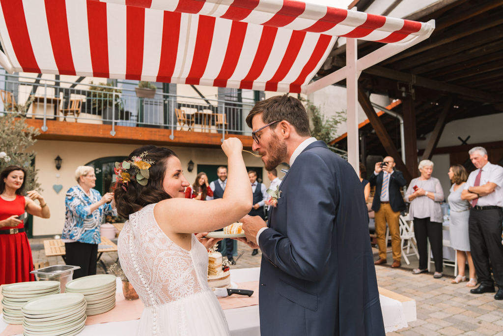 Brautpaar fttert sich mit der Hochzeitstorte.