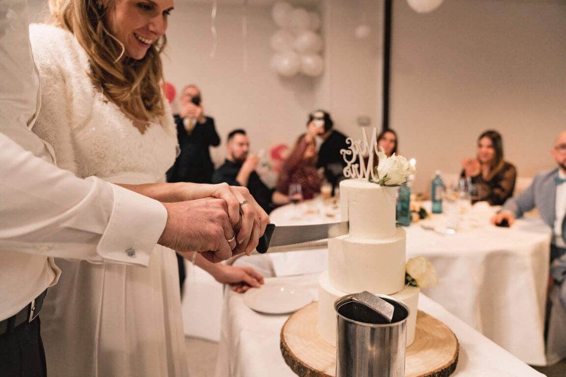 Brautpaar schneidet gemeinsam die Hochzeitstorte an