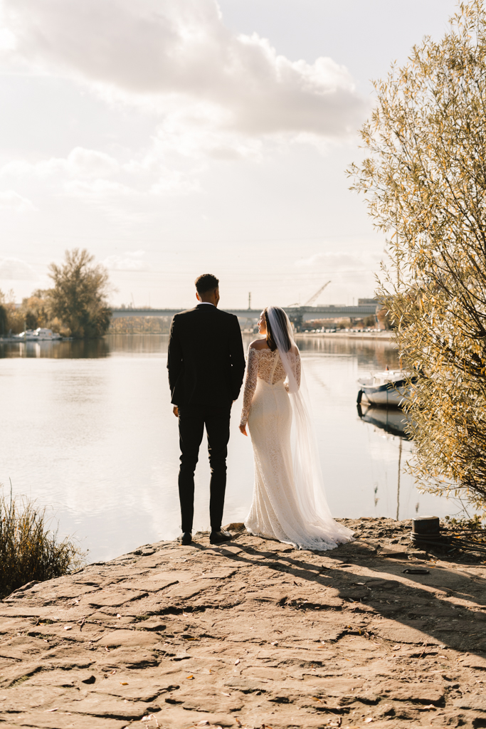 Hochzeitspaar steht an der Landzunge vom Main und schaut auf Wasser.