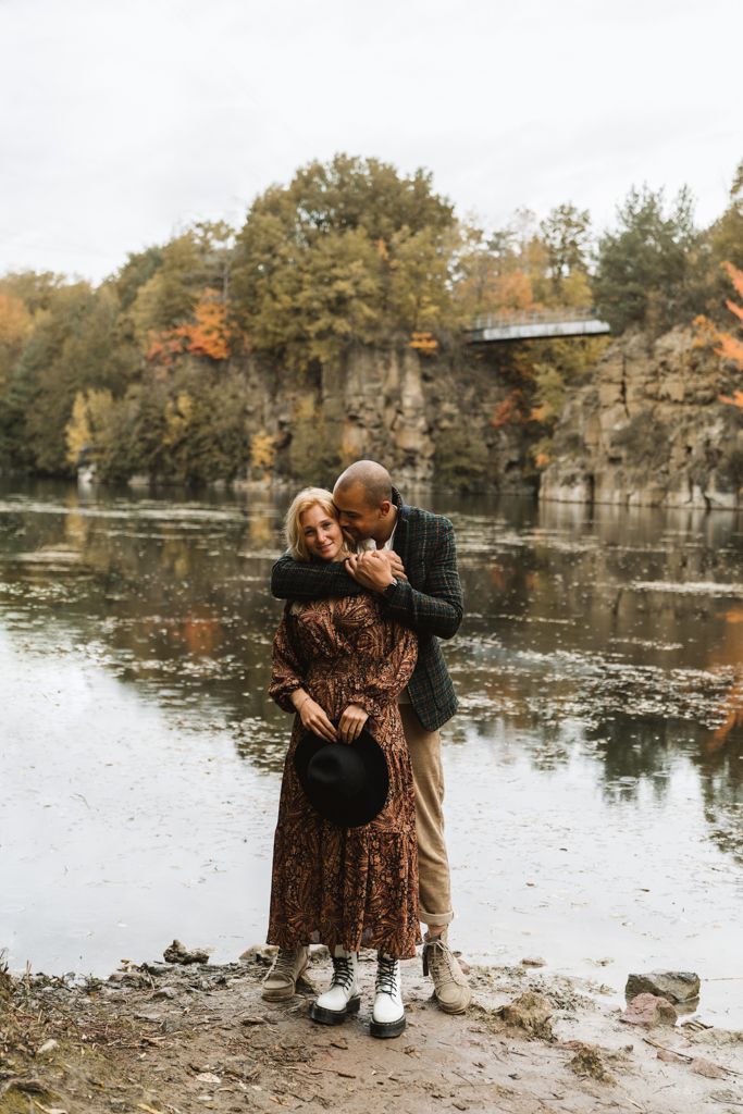 Pärchen steht an einem See in herbstlichen Farben.