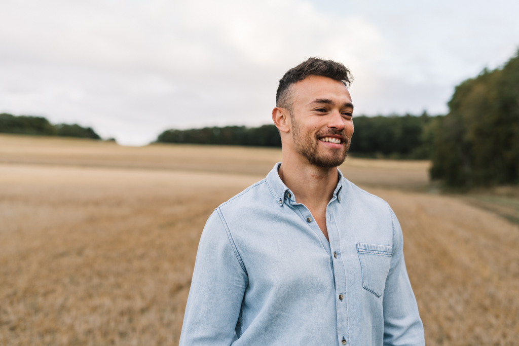 Mann im blauen Hemd steht auf einem Feld.