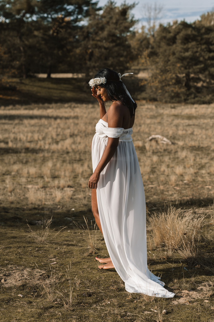 Braut steht in den Dünen im weißen Kleid und Haarkranz.