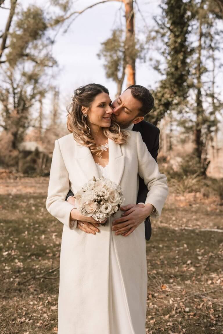 Winterhochzeit Brautpaarshooting Bräutigam küsst seine Braut auf die Backe