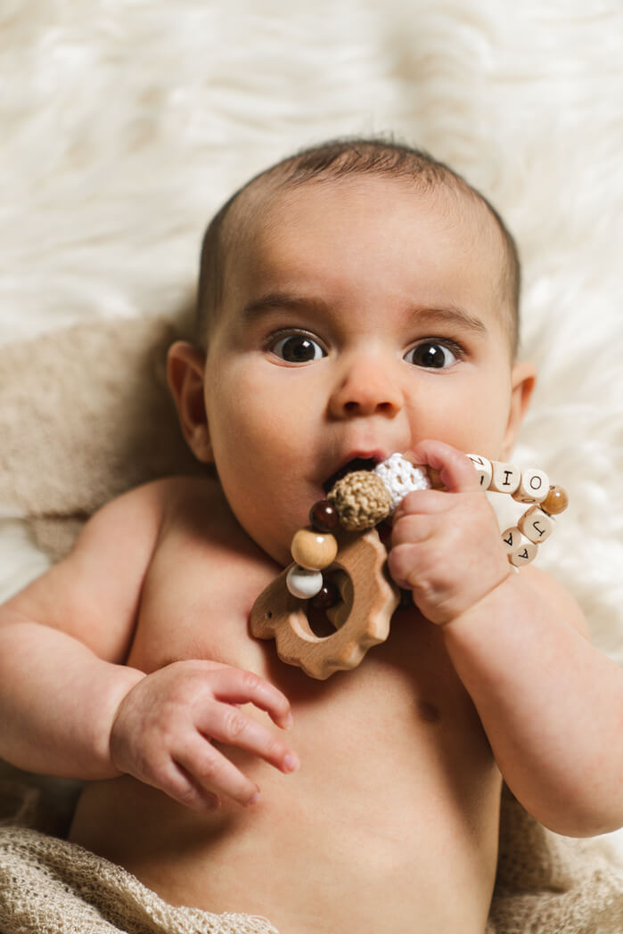 Baby kaut an der Schnuller kette während des Babyshooting.