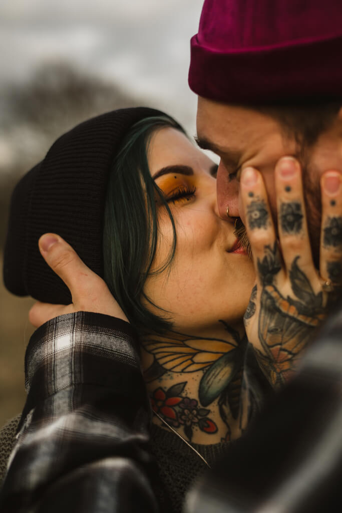 Nahaufnahme von einem Paar mit Tattoos das sich küsst.