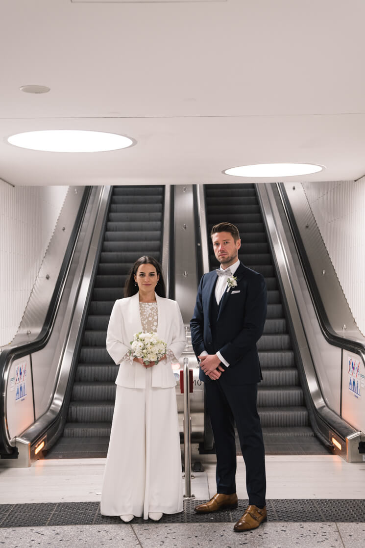 Brautpaar steht vor einer Rolltreppe in einem U-Bahn Schacht.